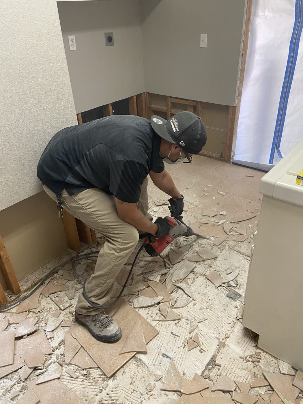 Home Doctors Restoration crew member removing damaged tile flooring