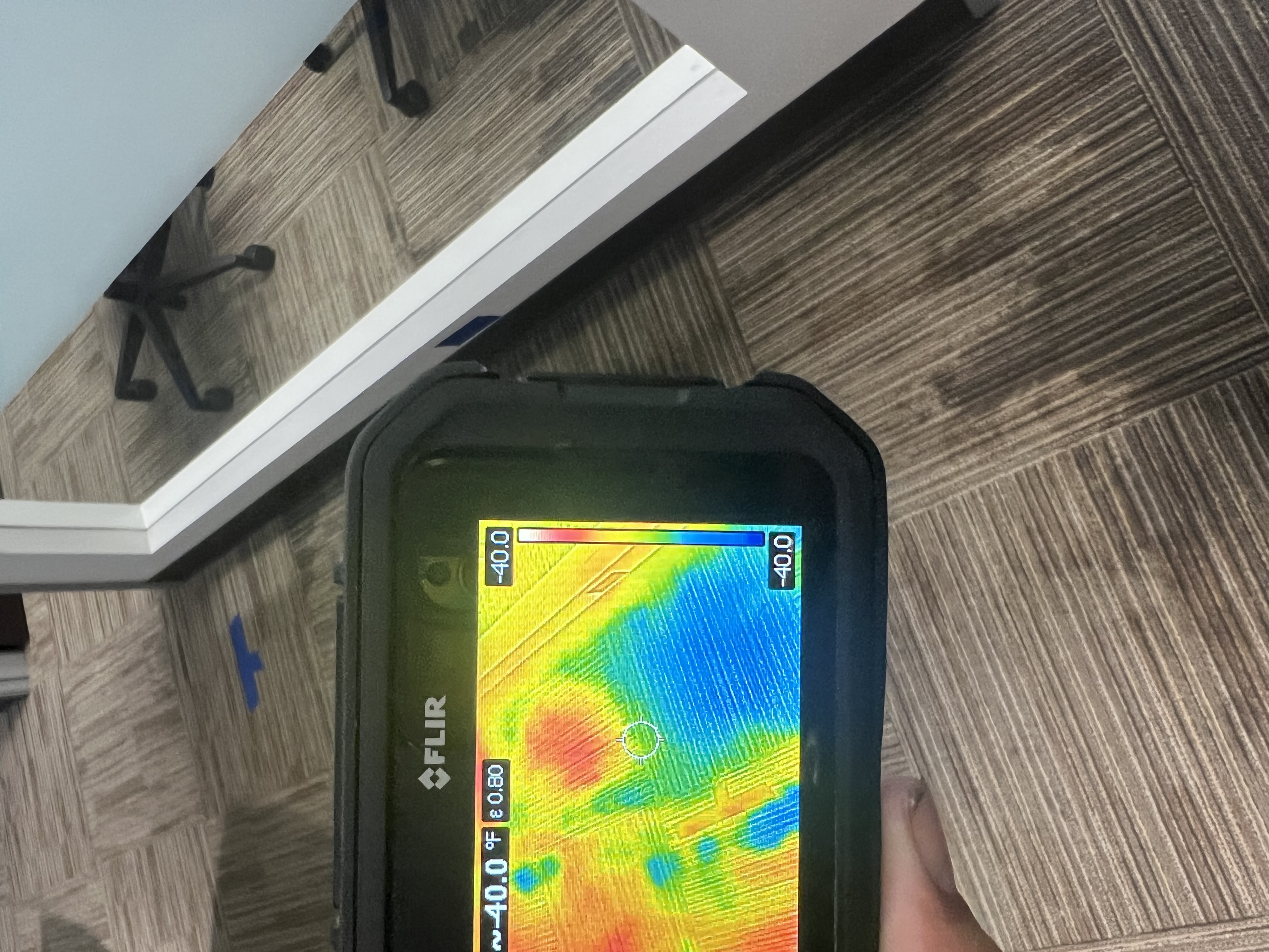 Thermal camera scanning carpet near an office desk for hidden moisture